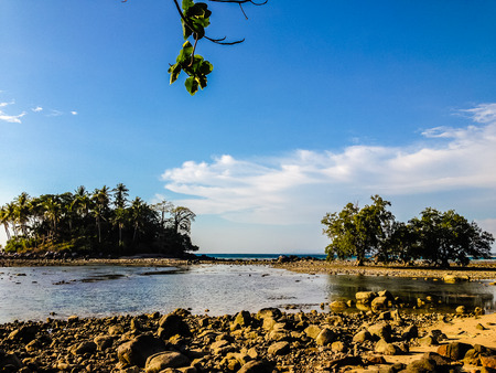 Lonely remote island with rock beach and tree when the sea water receded in blue sky and cloudy day backgroundの写真素材