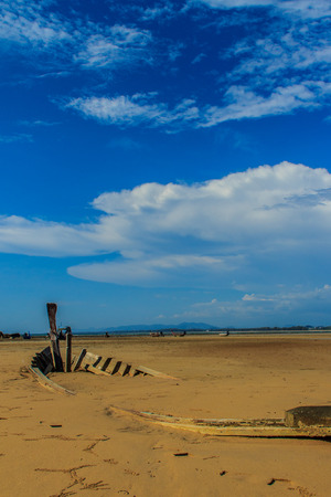 Old wreck fishing boat buried in the sand with blue sky on cloudy day backgroundの写真素材