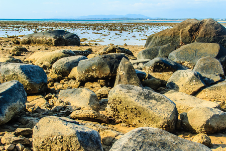 Beautiful rock stones on the beach when the sea water receded with dramatic blue sky background on the cloudy day.の写真素材