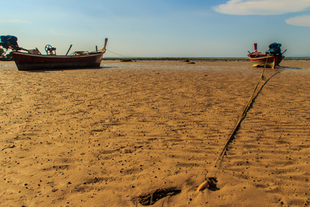 Traditional Thai wooden longtail boats (Rua Hang Yao) moored on the sand at small pier with blue sky and small island background in Phuket, Thailandの写真素材