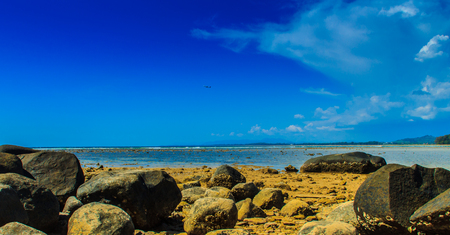 Beautiful rock stones on the beach when the sea water receded with dramatic blue sky background on the cloudy day.の写真素材