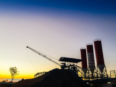 Cement concrete mixing production factory in silhouette with morning light and blue sky backgroundの写真素材