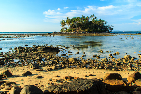 Lonely remote island with rock beach and tree when the sea water receded in blue sky and cloudy day backgroundの写真素材