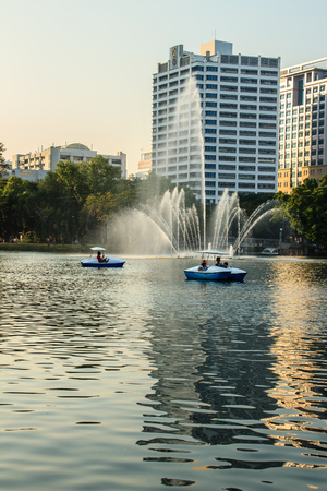 Beautiful fountains in the lake at Lumpini Park, Bangkok Thailand. Tranquil public park garden with pond, fountain, and boats in the middle of the city for people on holiday or after work leisured.のeditorial素材