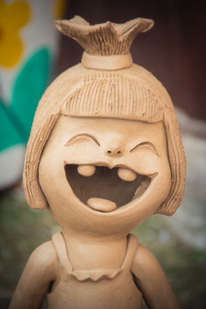 Happy Ceramic dolls for garden decoration. Cute ceramic clay pottery of girl show her up-swept bun and broken tooth that happy laughing until her eyes closed. Happy dolls for garden decoration.の写真素材