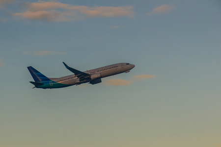 Airplane taking off from the runway airport, uprising with clouds in the blue sky backgroundの写真素材