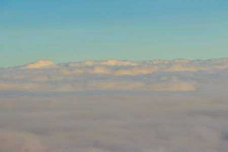 Beautiful cloudscape from sky aerial view. Beauty of nature view from above the sky and clouds. White clouds and blue sky view from airplane window. Sunlight in the sky shines on clouds.の写真素材