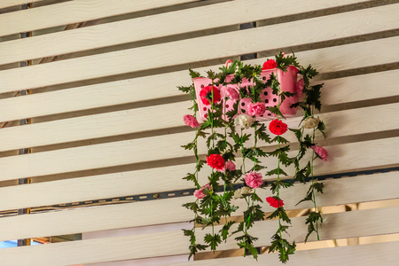 Beautiful artificial flower in the pot hanging on a white wooden wall for shop decorationのeditorial素材