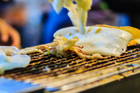 Closeup of Grilling squid, the Exotic Street foods at night market in Thailand. The squid grilled on fire for seafood buffet in the restaurant.の写真素材