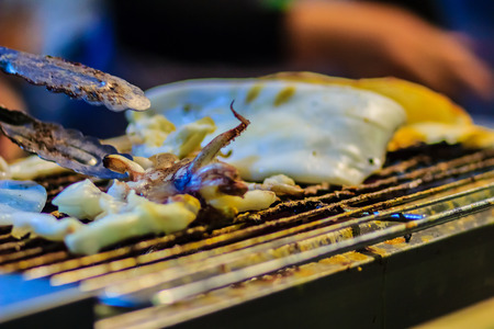 Closeup of Grilling squid, the Exotic Street foods at night market in Thailand. The squid grilled on fire for seafood buffet in the restaurant.の写真素材