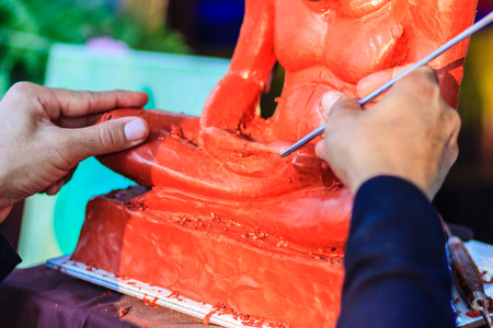 Sculptor carving the clay monk image. Thai sculpture artist molding and carving clay for making famous monk image. The craftsman concentrate to use the tools carving for art workの写真素材