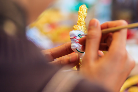Close up hand of Thai sculptor during painting the masterpiece of puppet patterns,の写真素材