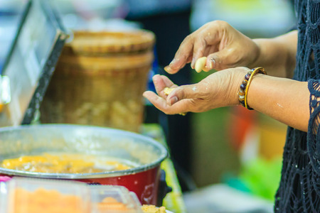 Close up hands of street vendor during cooking for "Kanom Khai Pla", Rice Flour Mixed with Toddy Palm and Shredded Coconut, Thai dessert, Thailandの写真素材