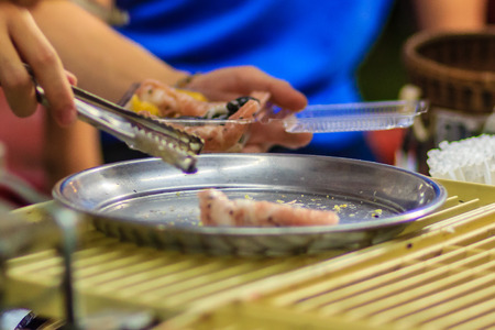 Close up hand of vendor during cooking for Crispy roll or tootsie Thai snack, Thai dessert Thai style food called "Thong muan" or "Tong Muan", a type of rolled wafer, a traditional dessert in Thailandの写真素材