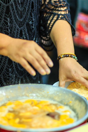 Close up hands of street vendor during cooking for "Kanom Khai Pla", Rice Flour Mixed with Toddy Palm and Shredded Coconut, Thai dessert, Thailandの写真素材