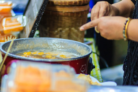 Close up hands of street vendor during cooking for "Kanom Khai Pla", Rice Flour Mixed with Toddy Palm and Shredded Coconut, Thai dessert, Thailandの写真素材