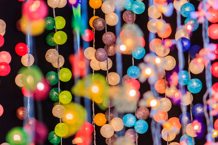 Beautiful curtain line of LED lighting with bokeh at night. Abstract line of LED light bokeh defocused background. Colorful decorative LED lights for sale in the night market at Bangkok, Thailand.の写真素材