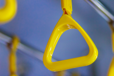 Yellow handles on ceiling rails for standing passenger. Handle on the MRT, prevent toppling.underground railway system or metro,people holding onto a handle on a train and the bus. Selective focusの写真素材