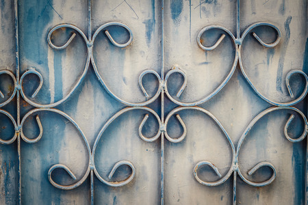 Old wrought iron bars on the gate with grunge and rusty steel  background. Iron Grill Ornamental Flourish Detail Background. The old rusty fence with metallic gate pattern, curved steel background.の写真素材