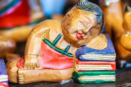 Cute collection of wooden sleeping girl on books, handicraft souvenir from Thailand.の写真素材