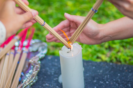 Close up hands lighting the incense sticks for made Brahma image worshipの写真素材