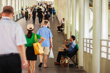 Bangkok, Thailand - February 22, 2017: Blind singer is singing a song for begging, while people are walking through this singer beggar without anyone going to donate money.のeditorial素材