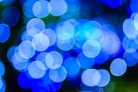 Beautiful blue bokeh abstract light background. Wonderful Defocused abstract blue christmas background. Abstract christmas lights as background in the night with noise grain and poor light.の写真素材
