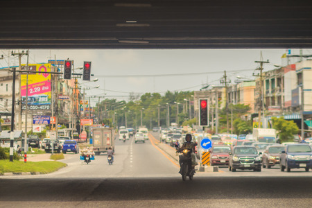 Chonburi, Thailand - May 23, 2017: The opposite motorbike is turning right while the going direct cars are waiting for red lights at the intersection.のeditorial素材