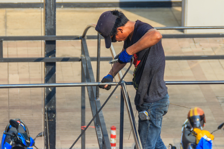 Bangkok, Thailand -March 8, 2017: A man is welded to a parking garage steel roof structure without protective equipment.のeditorial素材