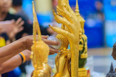 Close up hand of Thai people while bathing rite to buddha images in Songkran festival on the April 13 annual ritual every year. Buddhist is bathing a Buddha statue to gain merit during Thai New Year.の写真素材