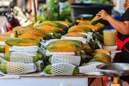 Extra jumbo size of ripe big yellow papaya fruit wrapped in protective net for sale at the fruit market in Bangkok, Thailand. Organic ripe papaya vendor is selling for extra large size at the stall.の写真素材