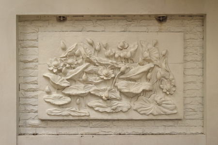 Beautiful white lotus stucco patterned on the boundary wall. Vintage white wall bas-relief stucco in plaster, depicts Lotus flowers background.の写真素材
