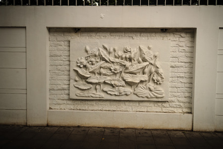 Beautiful white lotus stucco patterned on the boundary wall. Vintage white wall bas-relief stucco in plaster, depicts Lotus flowers background.の写真素材