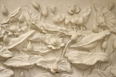 Beautiful white lotus stucco patterned on the boundary wall. Vintage white wall bas-relief stucco in plaster, depicts Lotus flowers background.の写真素材