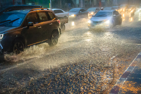 Bangkok, Thailand - July 6. 2017: Driving car through the heavy rain in the evening. Traffic under heavy rain with hail in dangerous situation with low visibility, slippery and splashing water.のeditorial素材