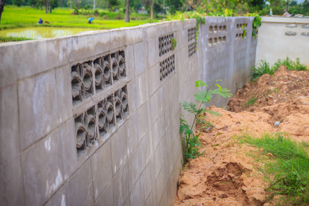 Fence wall of the newly built housing is tilted and collapsed due to high earthwork and heavy rainfall, causing the soil in the house to weaken and flow out with the water although there are drains.の写真素材