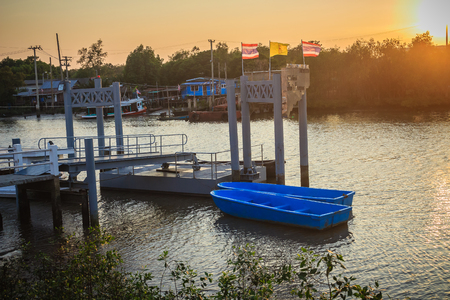 Moored blue boats with jetty at the side on canal in the evening sunset with Thai flags.の写真素材