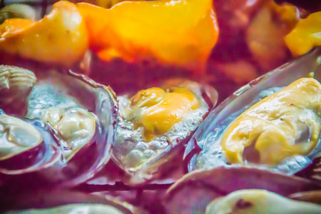 Grilled squids, mussels and clams on charcoal stove at night party. Seafood barbecue party with squid calamaris, mussels and clams are grilling on fire. BBQ concept, selective focus.の写真素材