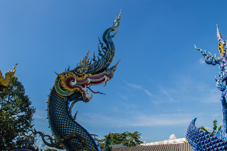 Beautiful blue naga sculpture with blue sky and white cloud on the sunny day at the public temple, Wat Rong Sua Ten, Chiang Rai, Thailand. Naga is a very great snake, found in the Buddhism temples.の写真素材