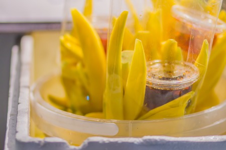 Yellow sliced mango in plastic bag with sweet sauce for sale at the fruit night market. Ready to eat sliced mango with sweet sauce in plastic bag for bring back home.の写真素材