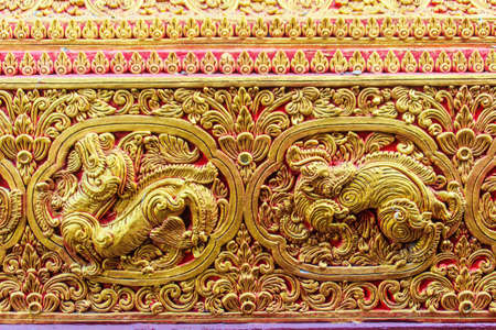 Beautiful golden carving of the mythical singha or lion on the sanctuary Buddhist church wall at Wat Srisupan, Chiang Mai, Thailand.のeditorial素材