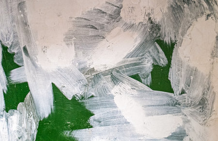 old concrete wall covered with textured plaster and painted with green paint. splashes of white...