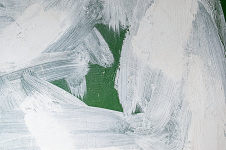 old concrete wall covered with textured plaster and painted with green paint. splashes of white...