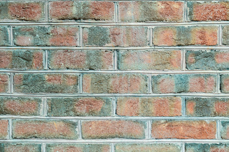 The wall of the building is made of dark, red to brownish clinker brick with various alternating patterns, close upの写真素材