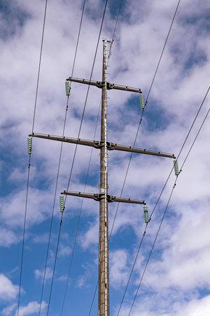 support for a high-voltage power line against the blue sky and sunlight, close up