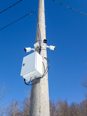Surveillance cameras mounted on utility pole under clear blue sky