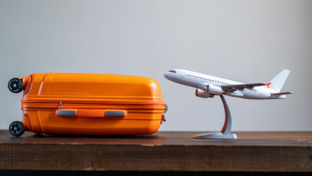 Orange Suitcase and Toy Airplane on Wooden Surface. generated by aiの素材