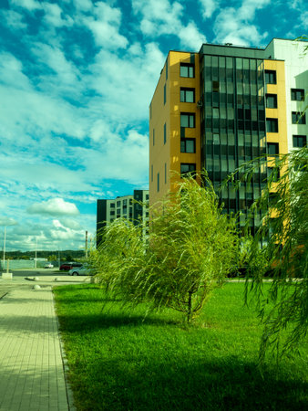 Modern buildings and greenery against a blue sky.の写真素材