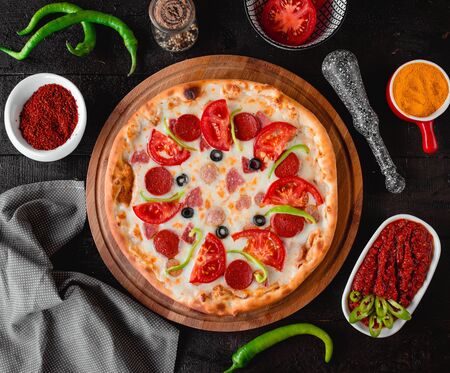 pizza with sausage tomatoes and olives top viewの写真素材