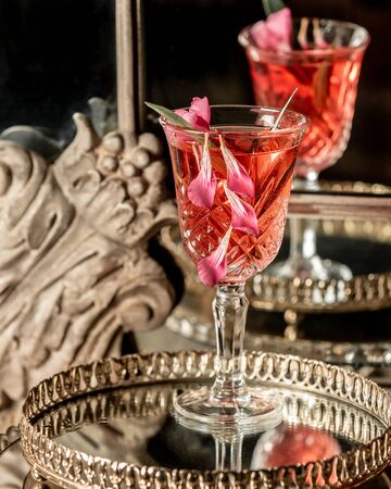 A drink in a glass with rose petals on a trayの写真素材
